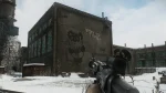 The image depicts a first-person view in the game "Escape from Tarkov," focusing on an industrial snowy scene with a large building prominently featuring a faded mural of a cartoonish bear with Cyrillic script. The environment is bleak and winter-themed, suggesting a harsh, post-Soviet setting typical of the game's realistic and immersive war-torn landscape. The player's perspective, equipped with a scoped rifle, adds a layer of tension and preparedness that is central to the game's survival and combat mechanics.