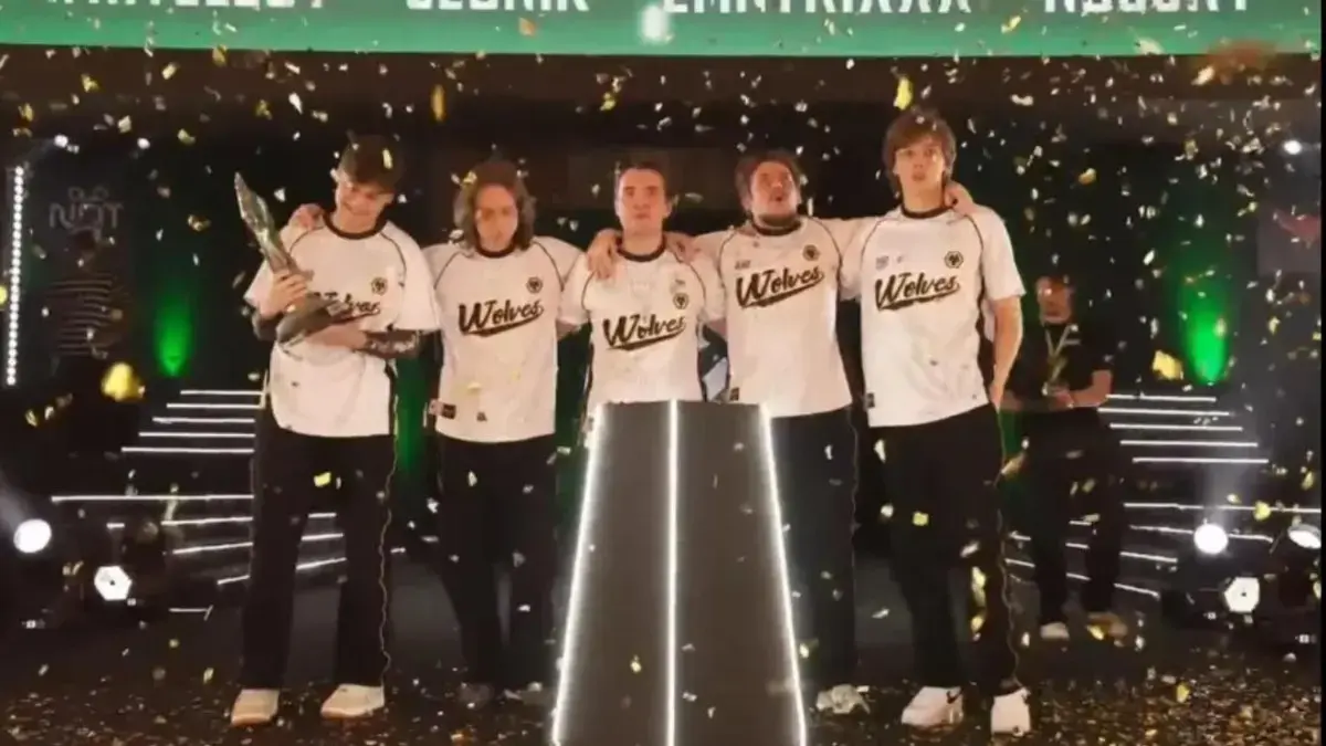 Wolves Esports players stand arm in arm under falling confetti as one of them holds the PMGO 2026 Season 2 trophy on stage in Lahore.